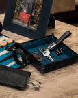 A luxury black leather key fob on a tray