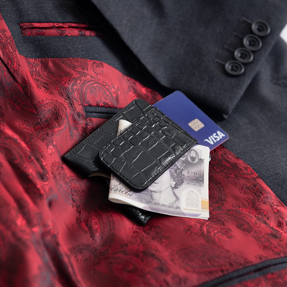 Black wallet with money and cards on a red fabric background